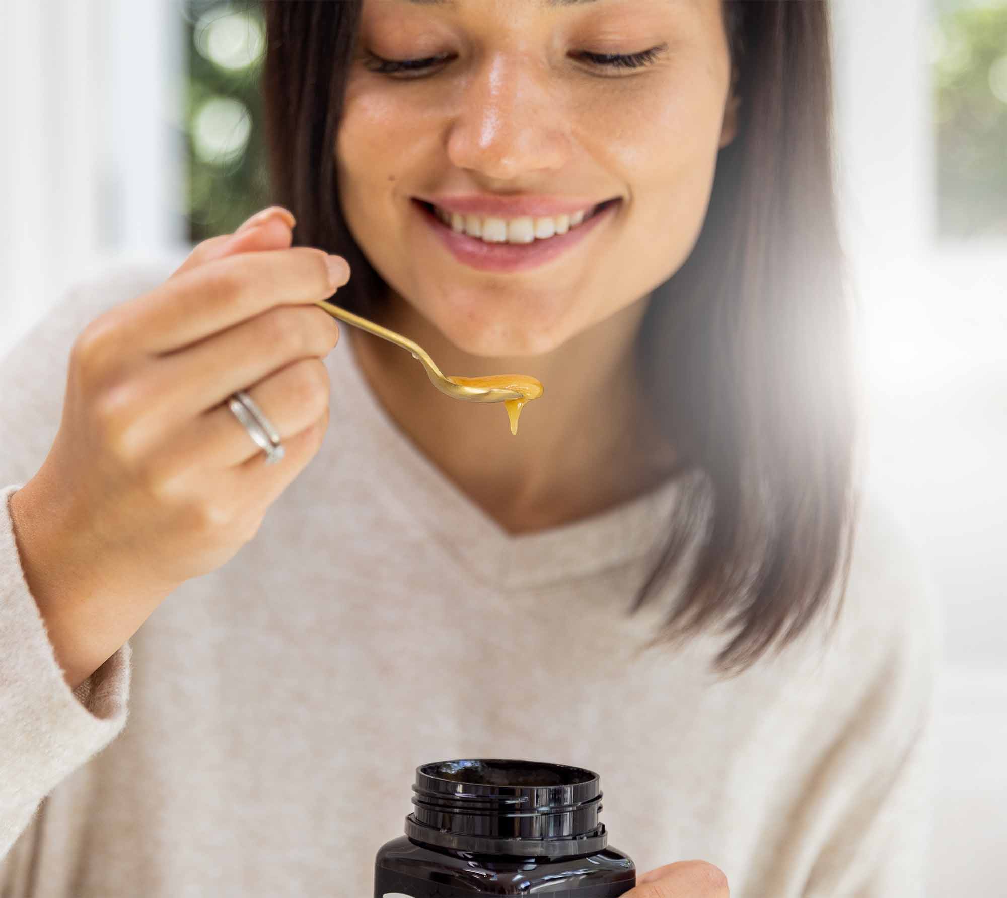 woman smiling and eating manuka honey